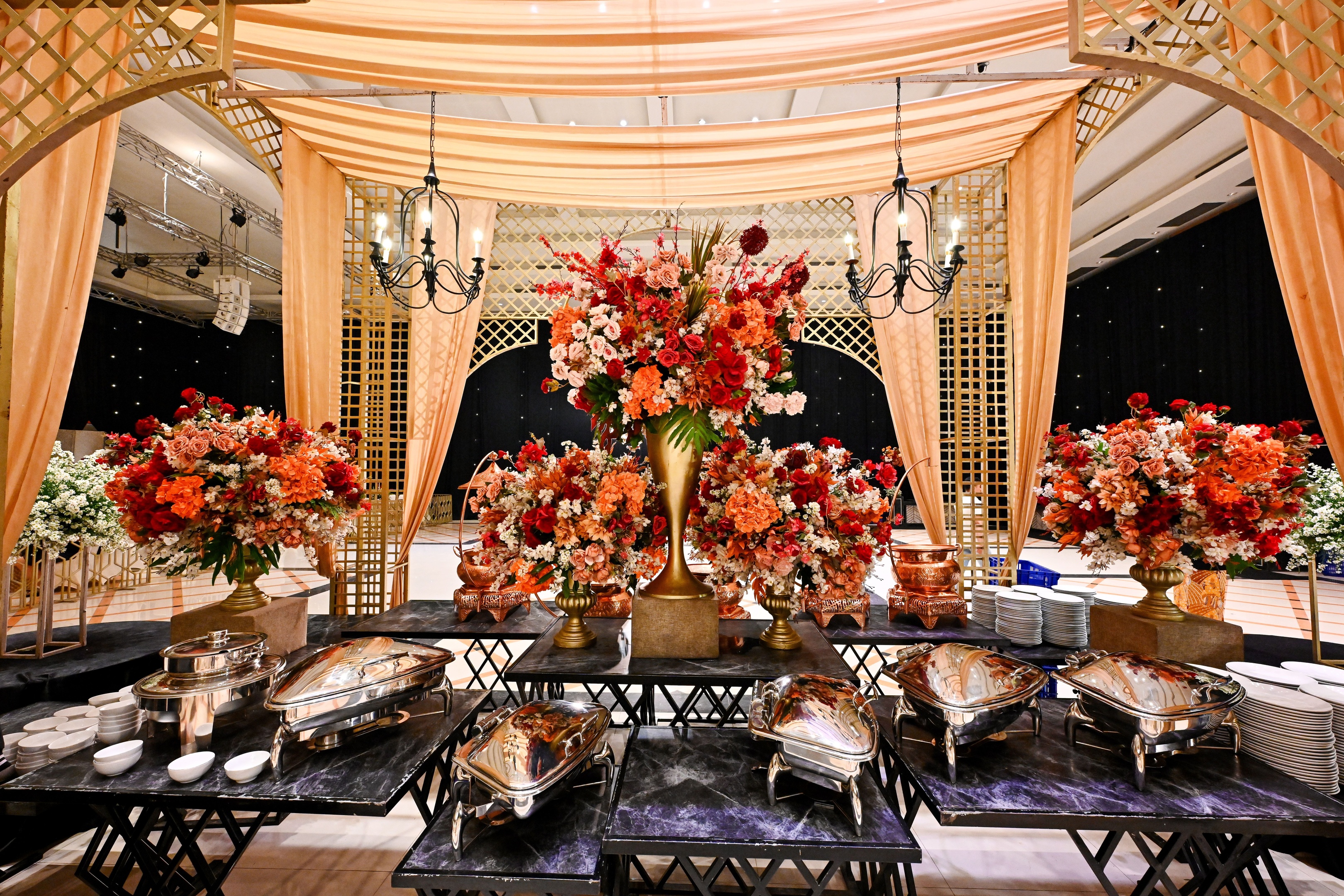 Event buffet with chafing dishes and floral centerpieces under draped canopy in Houston